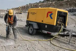 Worker using jackhammer on construction site