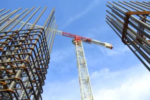 tower crane lifting construction materials at building construction site with steel reinforcement bars