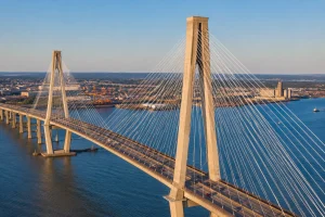 Cable-stayed bridge spanning river with tower cables and traffic in urban waterfront setting