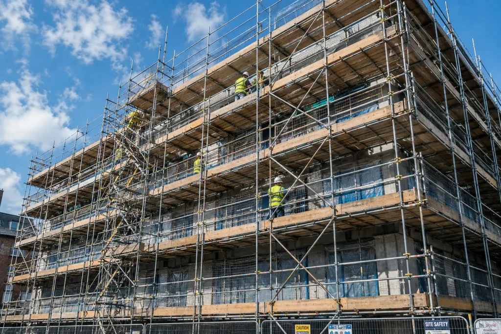 Tubular steel scaffolding installed on multi-storey building facade with workers on platforms