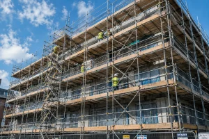 Tubular steel scaffolding installed on multi-storey building facade with workers on platforms