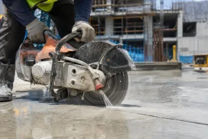 Worker wet-cutting concrete with a diamond blade saw