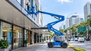 Knuckle boom lift reaching over a shopfront canopy to work on a building facade
